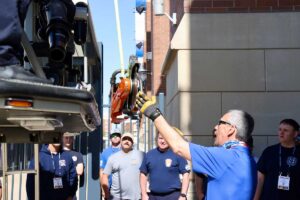 Mike Ciampo hands saw to firefighters in tower ladder bucket