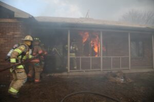 Firefighters make entry to a burning home